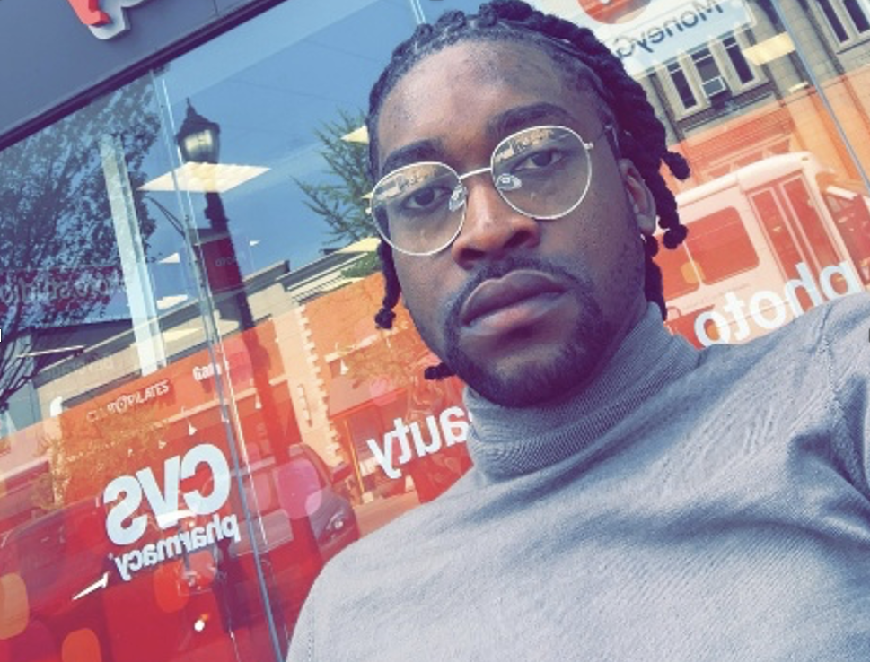 Chidubem Odinamkpa a dark skinned man wearing glasses and a grey turtleneck shirt.